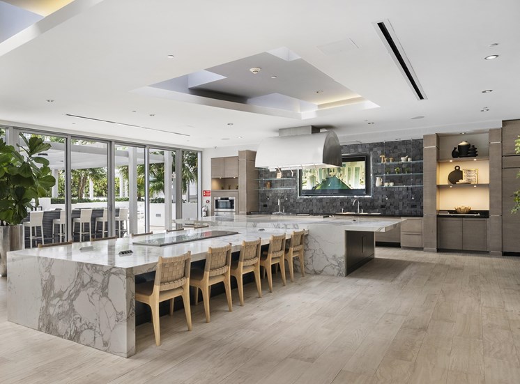A modern kitchen with a marble island and wooden chairs.